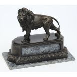 A 20th century bronze lion: raised on a shaped marble base, unsigned, 27cm. long.