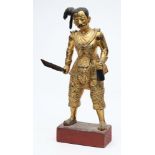 A South East Asian carved and gilded wood figure of a warrior: in traditional costume,