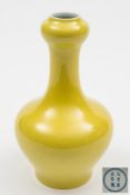 A Chinese yellow glazed garlic-necked bottle vase: the exterior covered with a bright yellow glaze,