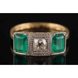 An 18ct gold, Art Deco style emerald and diamond three stone ring:, the central, cushion shaped,