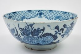 A large English blue and white delft punch bowl: painted in the oriental style with a bird, a fence,