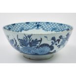 A large English blue and white delft punch bowl: painted in the oriental style with a bird, a fence,