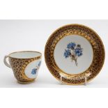 A Meissen porcelain cup and saucer: of ogee form each piece finely enamelled with a panel of three