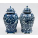 A pair of Chinese porcelain baluster jars and domed covers: painted in blue with panels containing