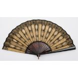 A 19th century tortoiseshell and sequin decorated fan: the black silk leaf with gilt gauze and