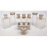 A set of nine French clear glass and silver mounted toiletry bottles: the tops monogrammed,