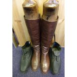 A pair of brown leather riding boots: with wooden trees and a pair of black leather clogs.