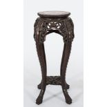 A Chinese carved hardwood circular jardiniere stand: the top inset with a panel of rouge variegated
