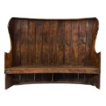 A 19th Century elm curved high back wing settle:, with plank back and concave solid seat,