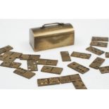 A set of novelty miniature brass travelling dominoes:, contained in a domed case, 3cm. long.