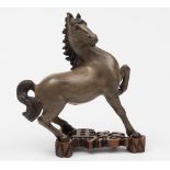 A Chinese stoneware figure of a horse: modelled in startled pose down on its rear quarters with one