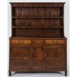 An 18th Century oak dresser:, the shelved superstructure with a moulded cornice,