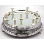 An Edwardian electro-plated wedding cake stand: of circular outline with mirror plate to the top,