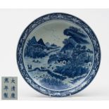 A Chinese porcelain shallow dish: of circular form painted in blue with an extensive landscape