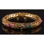 An Indian style emerald and ruby mounted bangle: with cabochon and circular-cut emeralds and rubies,