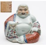 A Chinese porcelain figure of a seated Buddha: in typical posture wearing a brick decorated robe