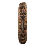 A Papua New Guinea carved and painted wood shield: carved and painted with stylised masks,