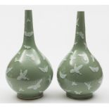 A pair of Chinese celadon glazed bottle vases: each decorated in white enamel with butterflies,