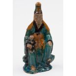 A Chinese sancai glazed seated figure of Guanyin: wearing flowing robes and with a child on one