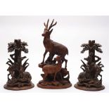 A pair of Black Forrest carved linden wood stands: decorated with stags and does below trees,