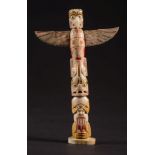 An American North Westcoast marine ivory miniature totem pole: carved and stained with stylised