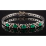 An emerald and diamond mounted bracelet: with five oval emeralds separated by cinquefoil clusters