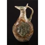 A Roman mould-blown olive green glass flask: of flattened form with a mask head to each side and