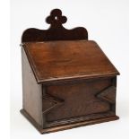 A 19th century oak candle box: the shaped backplate with sloping hinged lid and moulded geometric