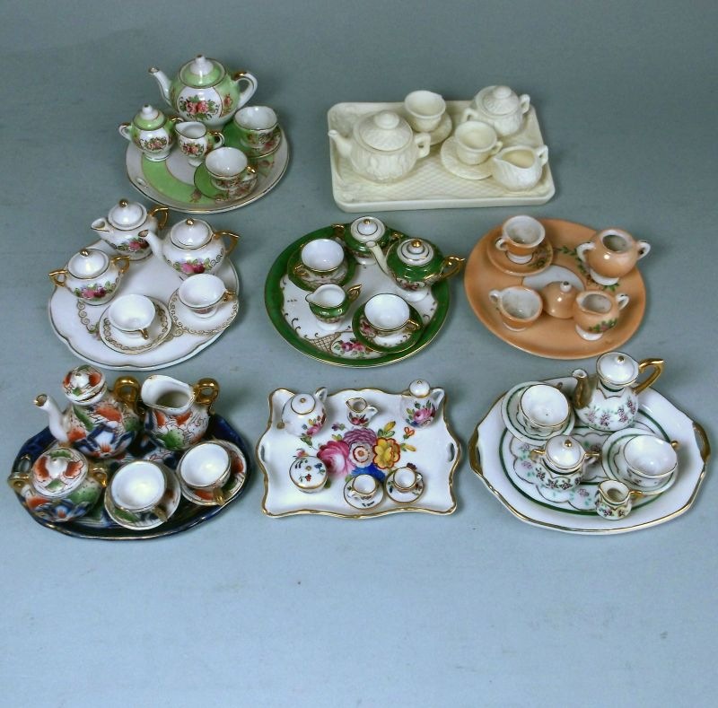 Eight miniature cabaret sets: comprising a bisque porcelain example on a rectangular tray,