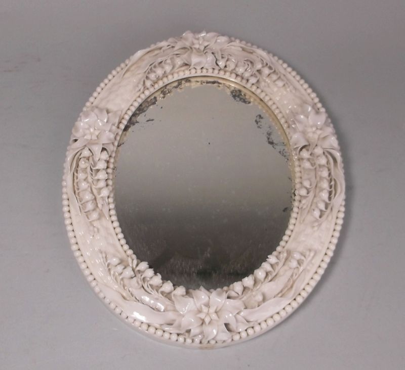 A Belleek porcelain oval Lily of the Valley mirror: first black mark, 27 cm high.