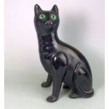 A Bretby pottery cat: modelled in seated posture with curled tail and inset glass eyes under a jet