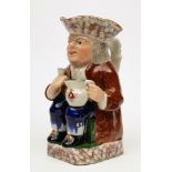 A pottery toby jug: modelled as a seated toper in tricorn hat,