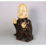 A Japanese brown glazed stoneware figure of Fukurokuju: the smiling god holding a scroll in his
