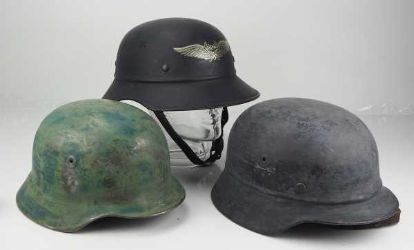 4.1.) Uniformen / Kopfbedeckungen Drei Stahlhelme.Gladiatorhelm in ungetragenem Zustand; dazu zwei