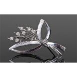 18 carat white gold and diamond set brooch, the leaf design with seven diamond flower heads, 50mm
