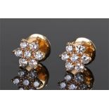 Pair of yellow metal diamond set earrings, each earring with seven diamonds to form a flower head,