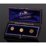 Set of three cased 15 carat gold buttons, in the form of flowers, cased
