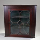 George III mahogany corner cabinet of wide proportions. The astragal glazed door enclosing shaped