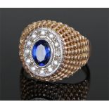 9 carat gold and sapphire ring, the central sapphire surrounded by stones, pierced sphere