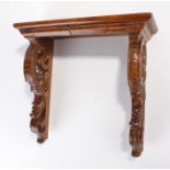 19th Century walnut bracket. The rectangular top above scroll and leaf carved supports, 32cm wide