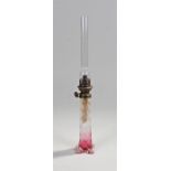 Slender glass oil lamp, the glass chimney above a brass fitting, clear to red glass base, 46cm high