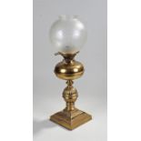 Frosted glass and brass oil lamp, the foliate frosted glass shade above a brass reservoir and fluted