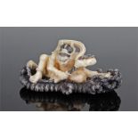 Finely carved 19th Century ivory netsuke, carved with a man crouched on a black stained robe raft,