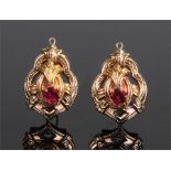 Pair of 9 carat gold earrings, with a central red stone surrounded with scrolls and buckles, 30mm