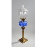 Blue and clear glass oil lamp, the glass chimney above an etched shade and blue swirl effect