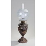 Silvered oil lamp, the frosted glass shade above a gadrooned and foliate decorated silvered base,