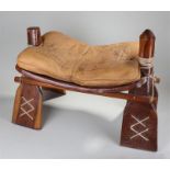 Egyptian camel saddle, the leather cushion above a carved and laced frame, 69cm long