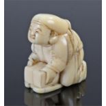 Meiji period ivory netsuke, carved as a figure crouched over a box, 37mm high