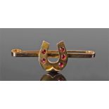 15 carat gold garnet set horse shoe brooch, with five garnets set to the shoe, 5.2cm wide, 5.8