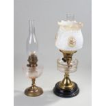 Two oil lamps, the first with a milk glass shade with foliate decoration above a clear glass